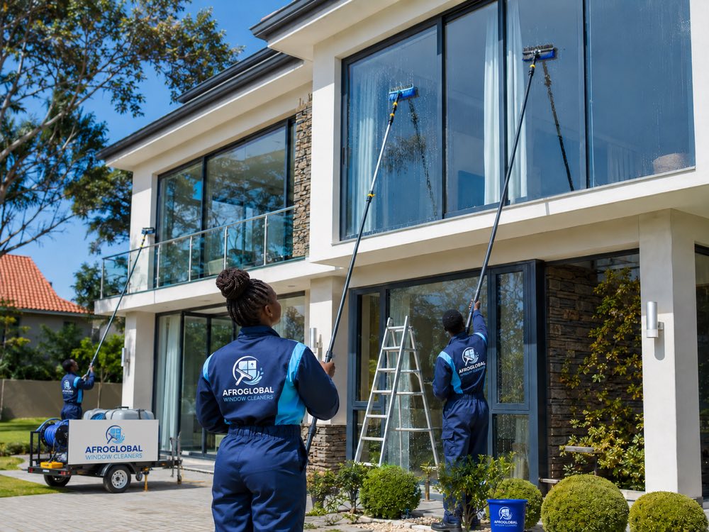 Cleaners washing the upper-floor windows of a double-storey home from the ground with telescopic hot-water poles